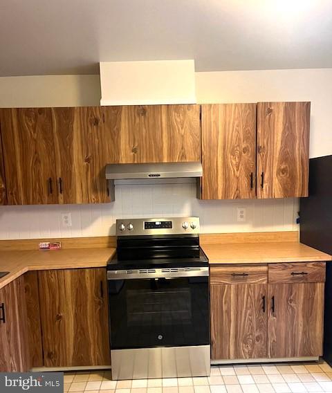 kitchen with black fridge, stainless steel range with electric cooktop, and extractor fan