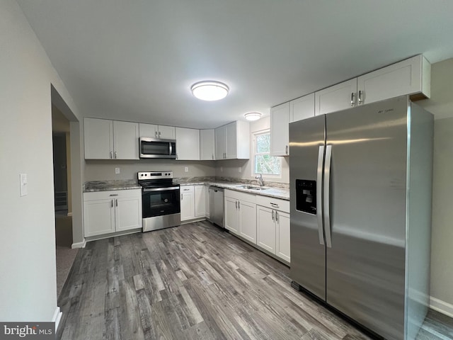 kitchen featuring white cabinetry, sink, light wood-type flooring, and appliances with stainless steel finishes