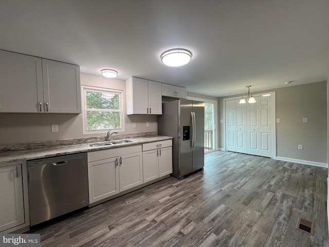 kitchen with sink, stainless steel appliances, a notable chandelier, wood-type flooring, and white cabinets