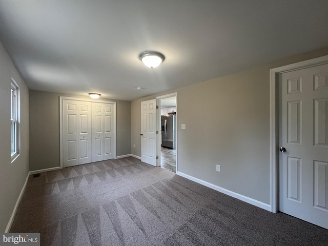 unfurnished bedroom with carpet flooring, stainless steel refrigerator with ice dispenser, and a closet