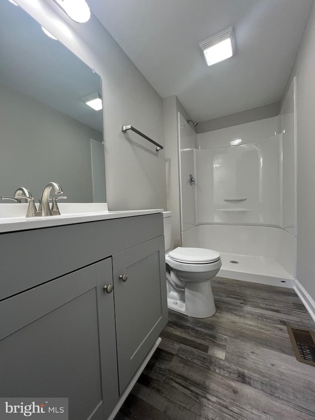 bathroom with wood-type flooring, vanity, toilet, and walk in shower