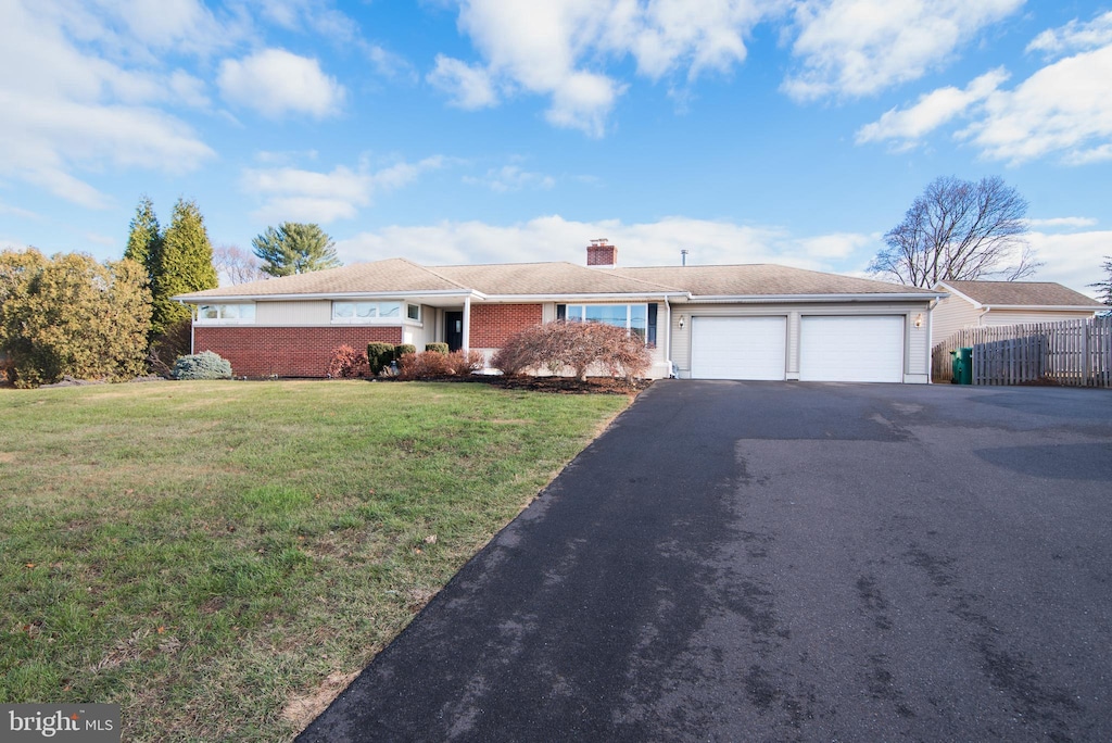 ranch-style home featuring a garage and a front lawn