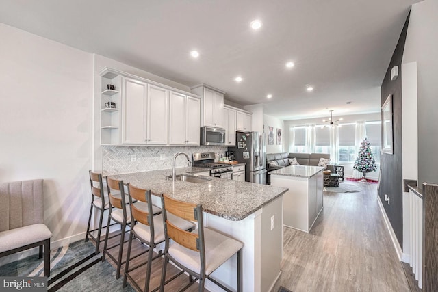 kitchen featuring a breakfast bar, white cabinets, decorative backsplash, kitchen peninsula, and stainless steel appliances