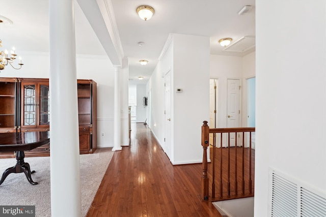 hall with an inviting chandelier, ornamental molding, ornate columns, and dark hardwood / wood-style floors