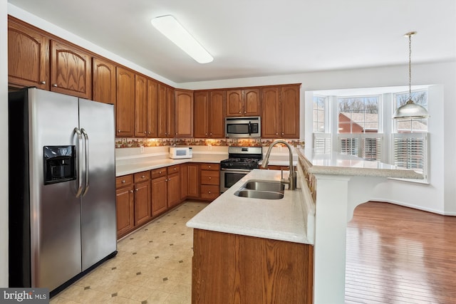 kitchen featuring kitchen peninsula, a kitchen bar, sink, hanging light fixtures, and appliances with stainless steel finishes