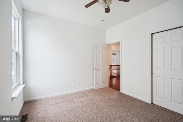 unfurnished bedroom with carpet floors, multiple windows, and ceiling fan