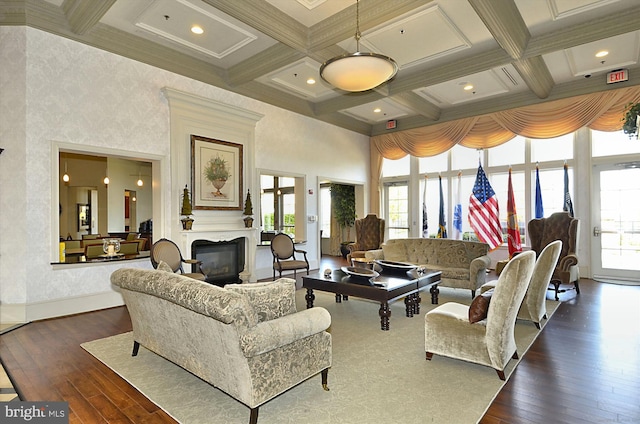 living room featuring a high ceiling, dark wood-type flooring, beamed ceiling, ornamental molding, and coffered ceiling