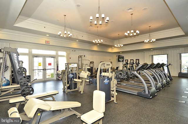 exercise room featuring a tray ceiling, ornamental molding, and french doors