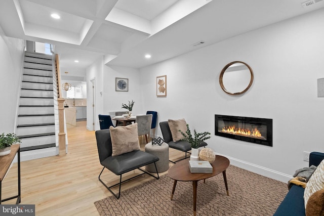 living room with beamed ceiling, light hardwood / wood-style floors, and coffered ceiling