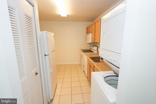 kitchen featuring sink, stacked washer and dryer, white appliances, and light tile patterned floors