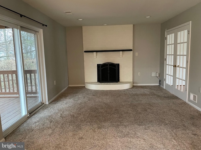 unfurnished living room with carpet flooring, french doors, and a brick fireplace