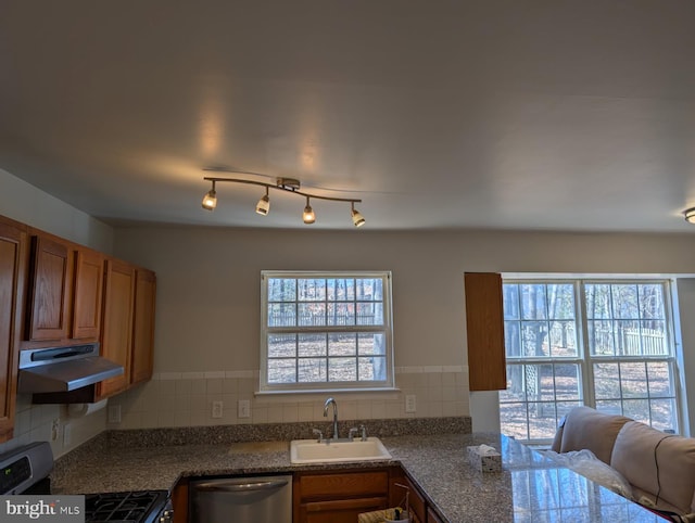 kitchen featuring stainless steel appliances, brown cabinetry, a sink, and under cabinet range hood