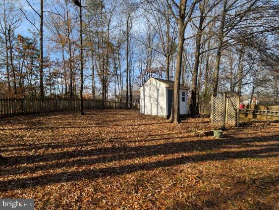 view of yard with fence, a storage unit, and an outdoor structure