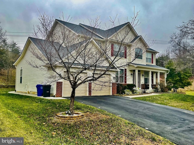 view of front of property featuring a porch, a garage, and a front lawn