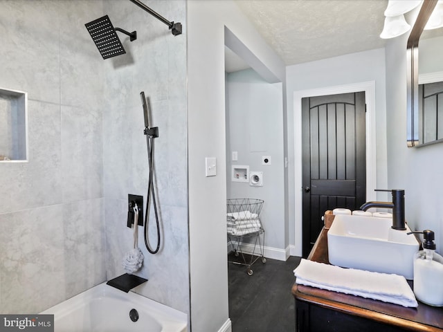 bathroom with vanity, hardwood / wood-style floors, tiled shower / bath combo, and a textured ceiling