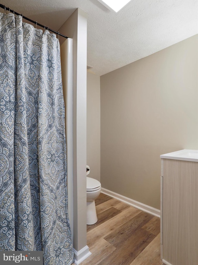 bathroom featuring toilet, hardwood / wood-style floors, and a textured ceiling