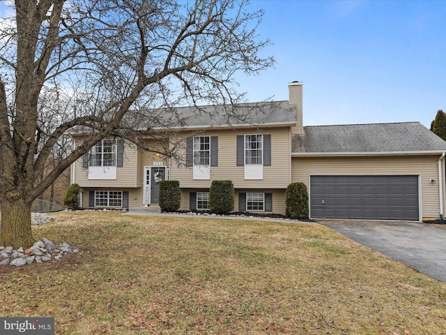 raised ranch featuring a garage and a front lawn