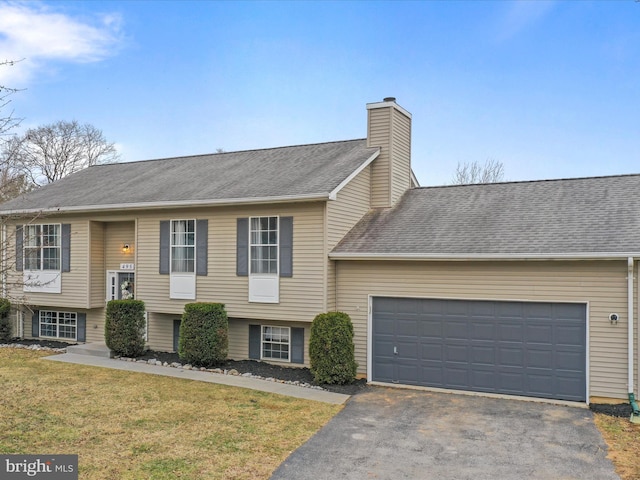 raised ranch featuring a garage and a front yard