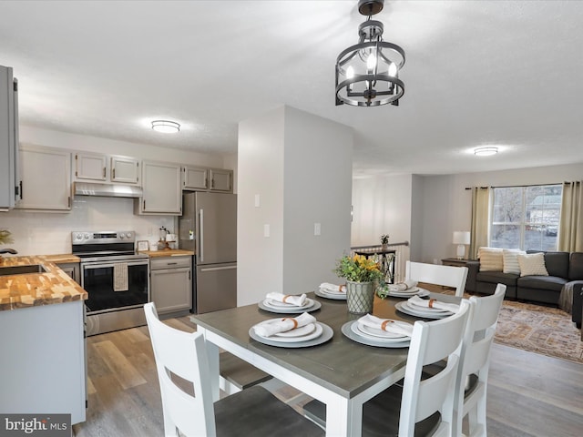 dining area with a chandelier, sink, and light wood-type flooring