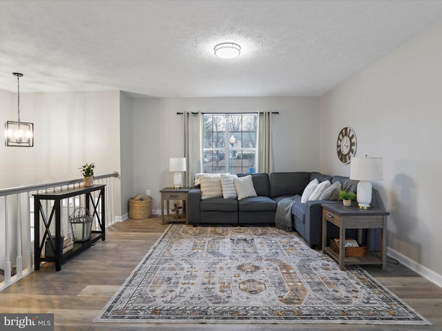 living room with an inviting chandelier, wood-type flooring, and a textured ceiling