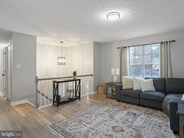 living room with hardwood / wood-style flooring, a textured ceiling, and a notable chandelier