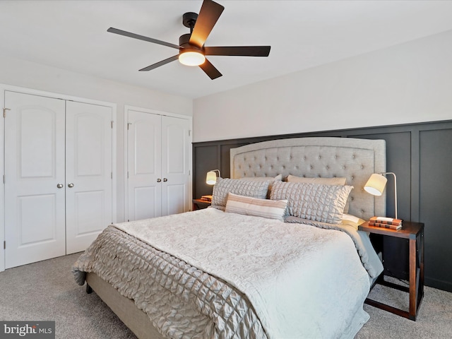 bedroom featuring ceiling fan, light carpet, and two closets