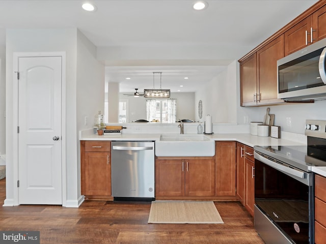 kitchen featuring ceiling fan, appliances with stainless steel finishes, decorative light fixtures, dark hardwood / wood-style flooring, and sink