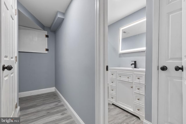 hallway with light hardwood / wood-style floors and sink