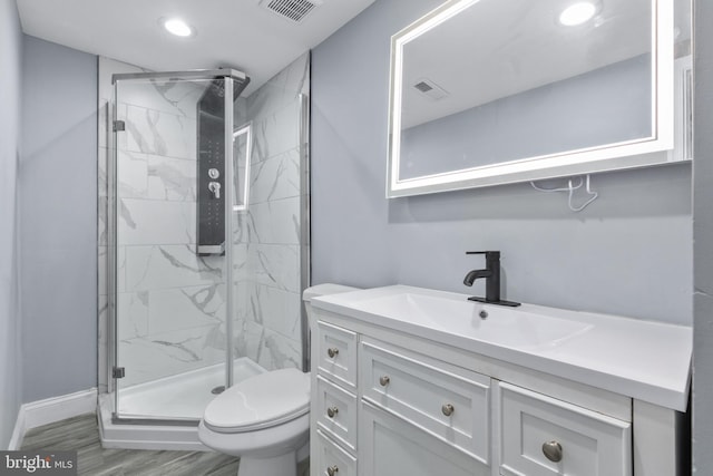 bathroom with hardwood / wood-style floors, vanity, toilet, and a shower with shower door