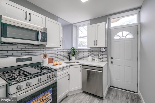 kitchen with backsplash, stainless steel appliances, white cabinetry, and sink