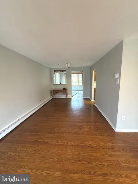 spare room with dark hardwood / wood-style flooring and a baseboard heating unit