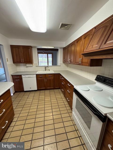 kitchen with white appliances, sink, light tile patterned floors, and custom range hood