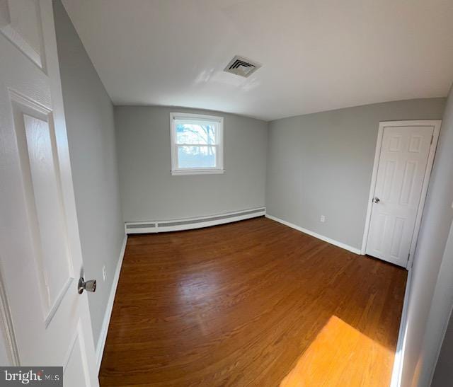 interior space with wood-type flooring and a baseboard heating unit