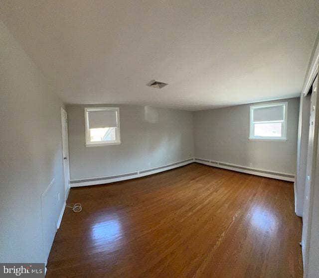 unfurnished room with dark hardwood / wood-style flooring, a healthy amount of sunlight, and a baseboard radiator