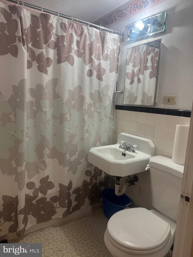 bathroom featuring sink, toilet, tile walls, and walk in shower