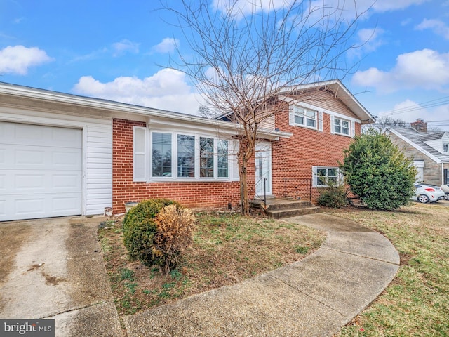 tri-level home with driveway, brick siding, and an attached garage