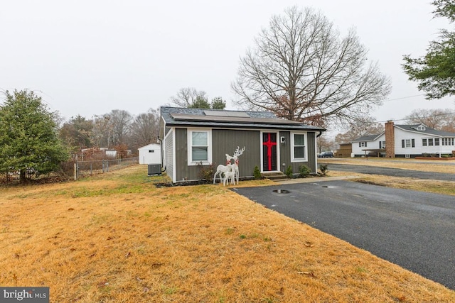 view of front facade with a front yard, solar panels, and central air condition unit