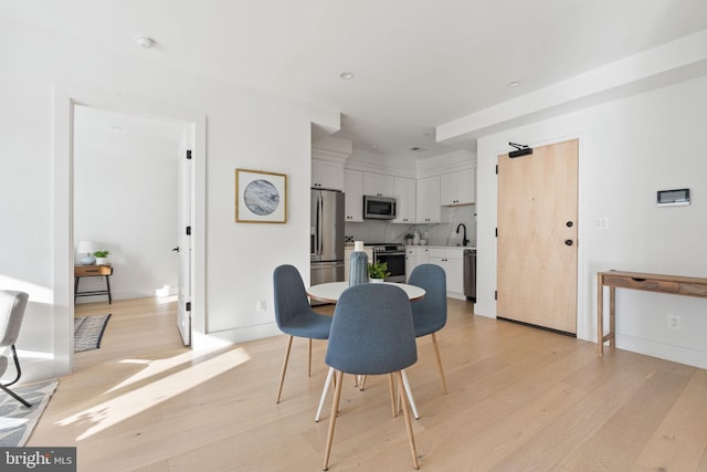 dining space with light hardwood / wood-style flooring and sink