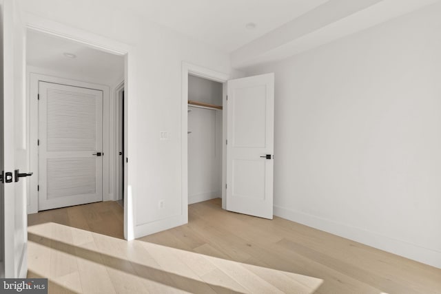 unfurnished bedroom with light wood-type flooring and a closet