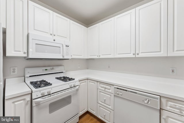 kitchen with white cabinets, wood-type flooring, and white appliances