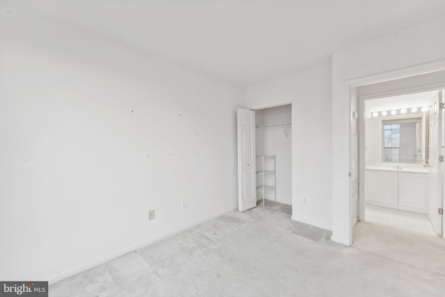 unfurnished bedroom featuring light carpet, ensuite bath, and a closet