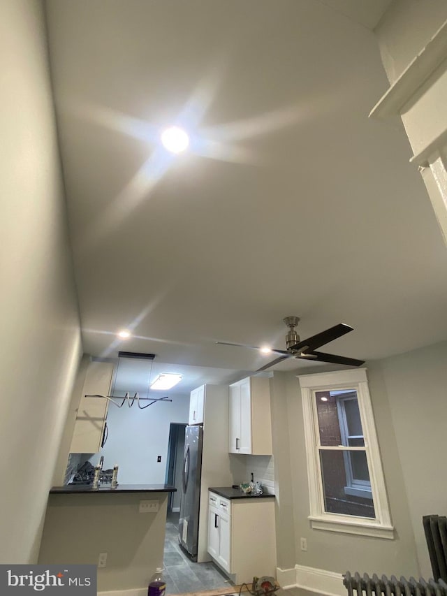 kitchen with white cabinets, stainless steel fridge, kitchen peninsula, and ceiling fan