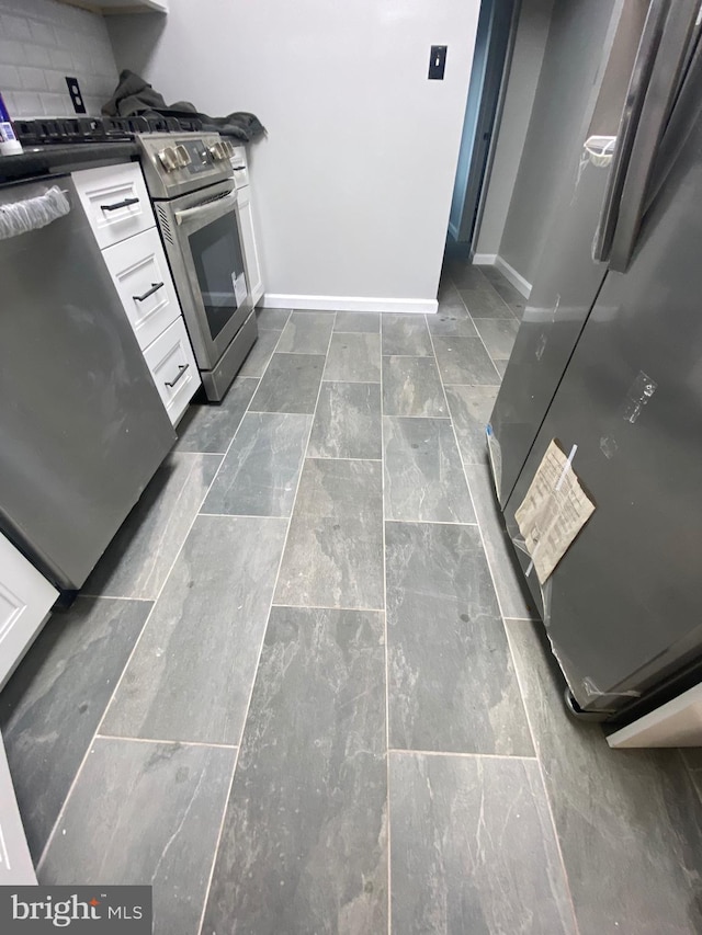 kitchen featuring decorative backsplash, refrigerator, white cabinetry, and stainless steel range with electric stovetop