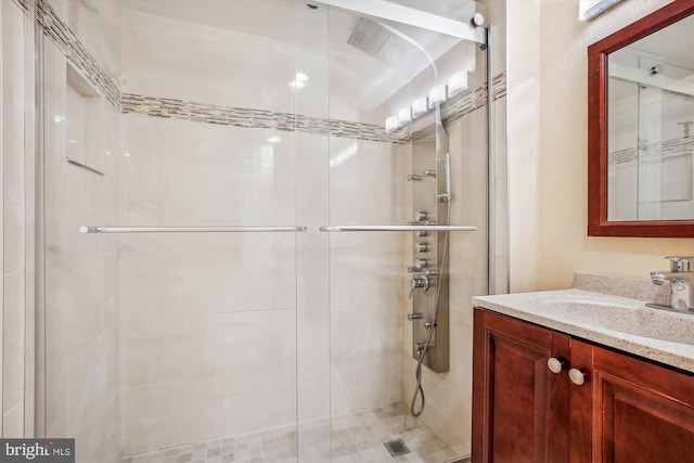 bathroom featuring a shower with door and vanity