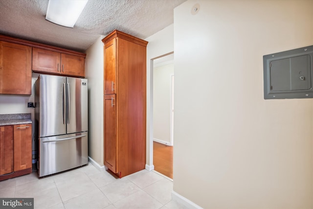 kitchen with stainless steel fridge, a textured ceiling, electric panel, and light tile patterned floors