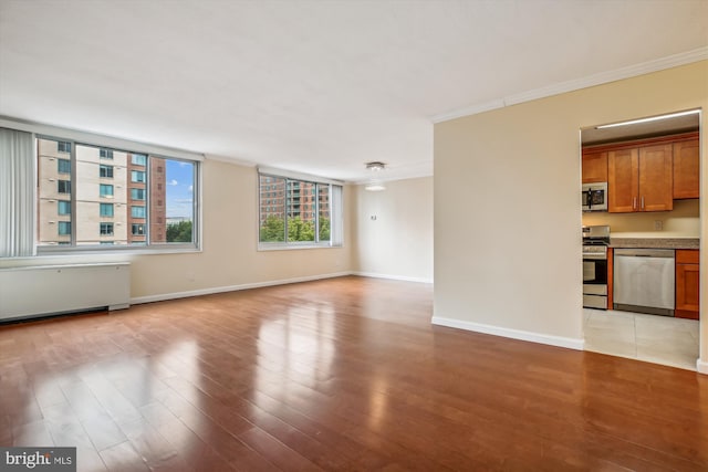 unfurnished living room with radiator, crown molding, and light hardwood / wood-style floors