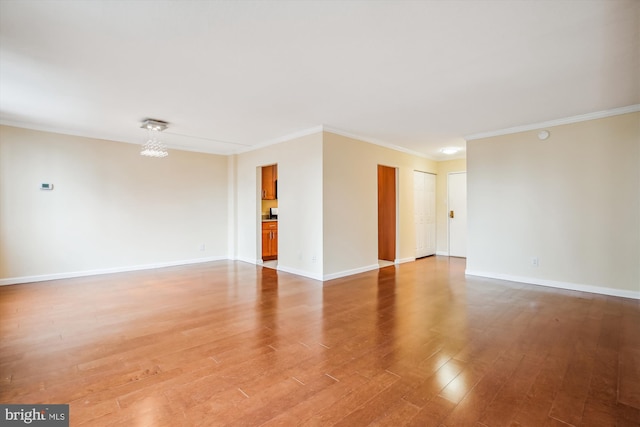 empty room featuring hardwood / wood-style floors, crown molding, and a chandelier