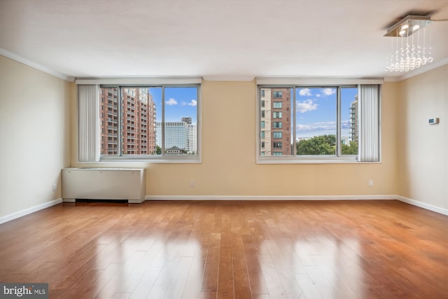 unfurnished room featuring crown molding, a chandelier, and light wood-type flooring