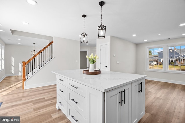 kitchen featuring a wealth of natural light, white cabinetry, light stone counters, and decorative light fixtures