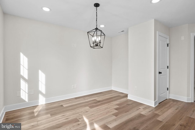 unfurnished dining area with light hardwood / wood-style floors and an inviting chandelier